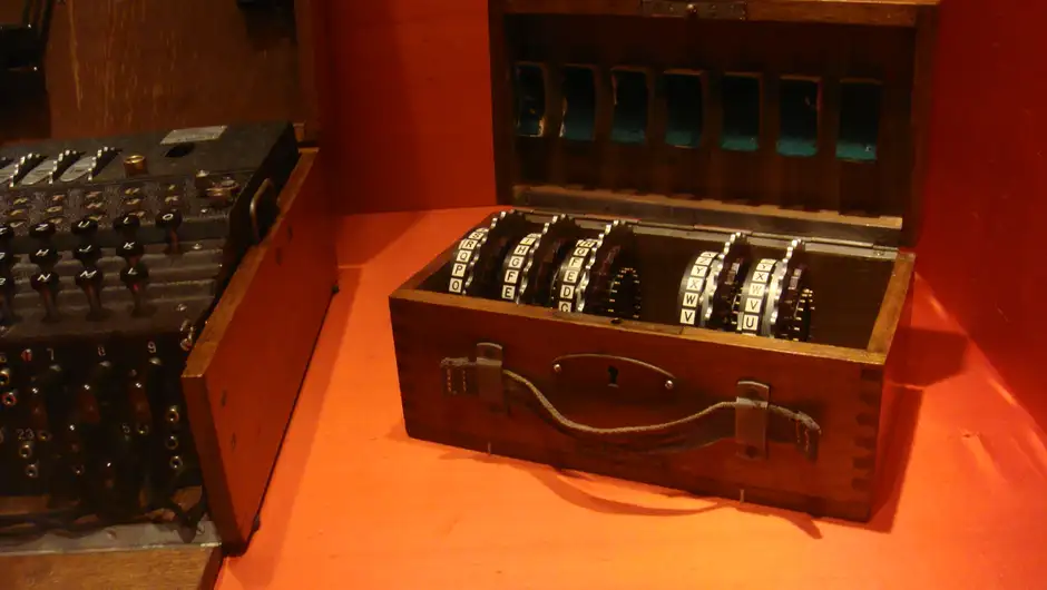 A German Enigma cipher machine in a wooden case, its lid open to show the keyboard and lettered rotors