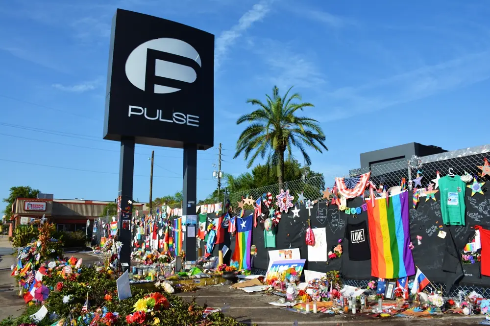 Memorials left on the fence of the Pulse nightclub: flowers, candles, and LGBTQ Pride flags
